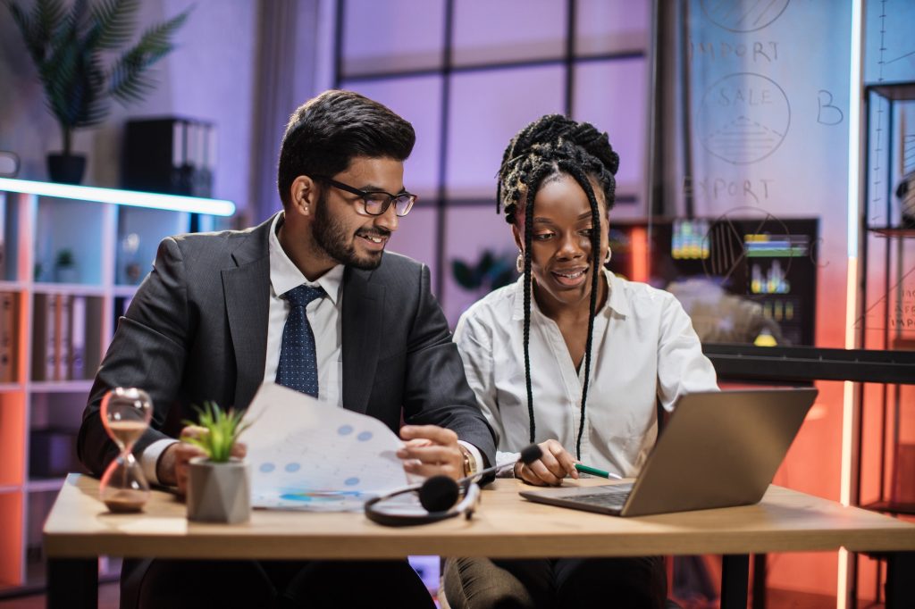 Two multicultural company workers arab financial expert and african woman office worker using laptop